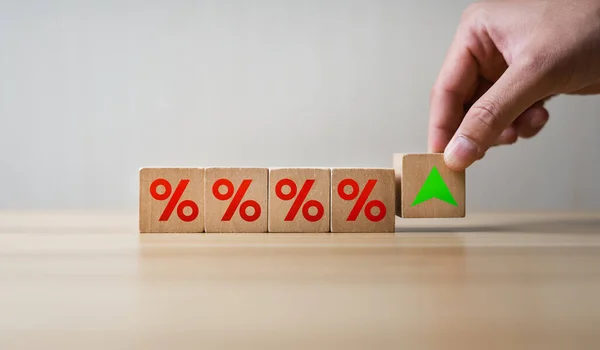 interest rates and dividends, mortgage rates, investment returns, income, retirement Compensation fund, investment, dividend tax. Hand placed rising cube stick and upward direction percentage symbol.