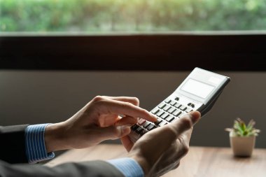 İş adamı ya da muhasebeci el hesap makinesi kullanarak, ofiste finans raporunu hesaplayarak, gelecekteki yatırımlardan uzun vadeli gelir elde etmek için finansal planlamaya ve tasarruf etmeye yardımcı olur.