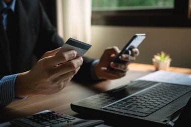 Kredi kartı kullanan bir işadamı, iş adamı ya da girişimci, online alışveriş, e-ticaret, mobil banka uygulaması kullanarak işlem yapıyor. çevrimiçi ödeme, e-ticaret için güvenli işlemler