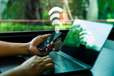 Modern İş Yeri 'nde Wi-Fi Bağlantı Hatalı Akıllı Telefon ve Laptop sahibi kişi. Aygıtlardaki Kırmızı Alarm Simgeleri tarafından sembolize edilen İnternet Bağlantı Sorunları, Bağlantı kurulamadı