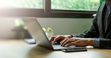 Modern Ofis Ayarlarında Uzaktan Çalışma, Verimlilik ve Odaklanma Gösterirken Dizüstü Bilgisayarda İşletme Profesyoneli Daktilo, Kusursuz İletişim ve Çoklu Görev Masasında Akıllı Telefon