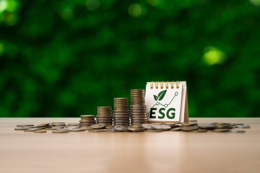 ESG investment growth concept with stacked coins and desk calendar displaying ESG acronym and rising chart, symbolizing sustainable finance, environmental responsibility, and long-term economic value