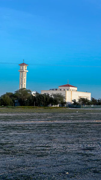 View of a mosque in the town of Kuwait with white clouds on blue