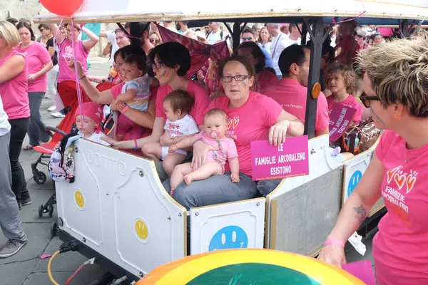 İtalya, Siena 'daki eşcinsel onur yürüyüşü sırasında sokakta pembe tişörtlü insanlar. Gay LGBTQ 'nun tezahürü. Çocukları olan kadınlar geyleri ve lezbiyenleri desteklemek için pankart taşıyorlar..