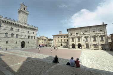 Büyük meydanda dinlenen turistler, Montepulciano 'daki saray komünü belediye binası, Toskana, unesco dünya mirası sahası.