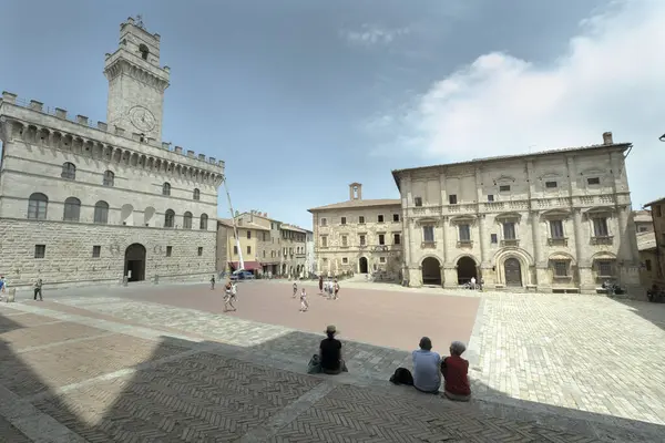 Büyük meydanda dinlenen turistler, Montepulciano 'daki saray komünü belediye binası, Toskana, unesco dünya mirası sahası.