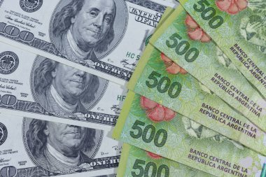 100 dolarlık banknotlar ve 500 Arjantin pesosu. Arjantin 'de dolar fiyatını yükseltmeye devam ediyor. Arjantin' de dolar fiyatını yükseltmeye devam ediyor..