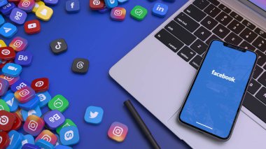 En önemli sosyal ağların rozetleriyle çevrili bir dizüstü bilgisayarda Facebook 'un simgesini gösteren akıllı bir telefonun 3 boyutlu görüntülenmesi.