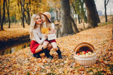 Kızı olan modaya uygun bir anne. Sonbahar parkında bir aile.