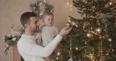 Mutlu genç baba Noel ağacının yanında oğluyla oynuyor. Birlikte kutlama, tatil konsepti.