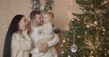 Mutlu aile babası ve bebeği evdeki Noel ağacında. Noel Ailesi. Mutluluk. Baba, anne ve oğul portresi.