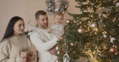 Mutlu aile babası ve bebeği evdeki Noel ağacında. Noel Ailesi. Mutluluk. Baba, anne ve oğul portresi.