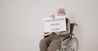 Yaşlı insanlar. Tekerlekli sandalyede oturan ve elinde aşı olan bir tahta tutan adam hayat kurtarıyor..