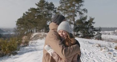 Genç, güzel, birbirine aşık kış şapkalı ve eşarplı çiftler kış ormanlarında birbirlerine sarılıp birlikte eğleniyorlar. Güneşli hava.