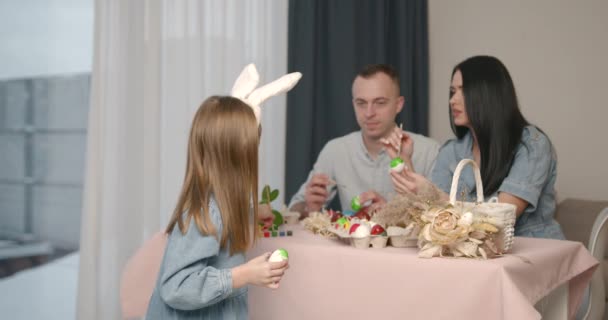 可爱的小女儿有小兔子耳朵花时间与她的父母 妈妈和爸爸画复活节彩蛋 玩彩笔 — 图库视频影像