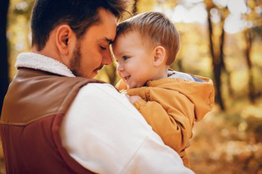 Aile sonbahar parkında eğlenir. Küçük oğlu olan yakışıklı bir baba.