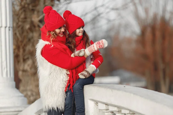 Aile Noel tatilinde örülmüş kış şapkalı anne ve çocuk. Anne ve çocuk için el yapımı yün şapka ve eşarp. Çocuklar için örgü örüyorum. Örgü dış giysi. Parktaki kadın ve küçük kız.