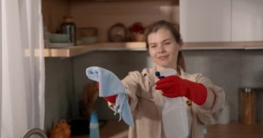 Güzel, yetişkin bir kadın, mutfağı bez ve spreyle temizliyor. Ev işleri konsepti, 4k video.
