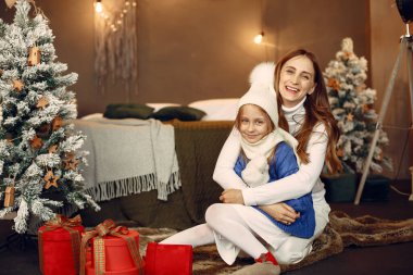 İnsanlar Noel için hazırlanıyor. Anne kızıyla oynuyor. Aile şenlik odasında dinleniyor. Mavi kazaklı çocuk..