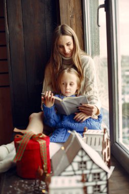 İnsanlar Noel için hazırlanıyor. Anne kızıyla oynuyor. Aile şenlik odasında dinleniyor. Mavi kazaklı çocuk..