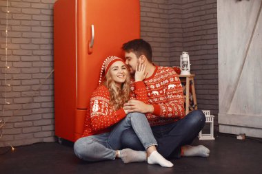 Noel süsü takmış insanlar. Kırmızı kazaklı bir adam ve kadın. Aile evde..