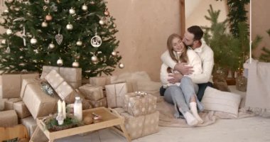 Mutlu Noeller ve mutlu tatiller. Noel tatili boyunca sevgi dolu bir çift Noel ağacının yanında sarılır..