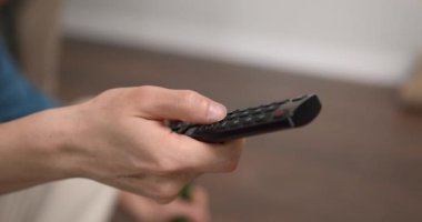 Mans elinde akıllı bir televizyon kumandası tutuyor. Arkadaşlar maç izledikten sonra yoruluyor.