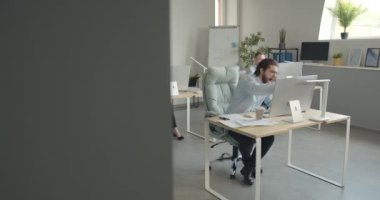 Ofiste çalışan genç bir iş adamı dizüstü bilgisayarı ve masa başında kağıtları var. İş arkadaşları arkada oturuyor. Şirket, iş, çalışanlar konsepti.