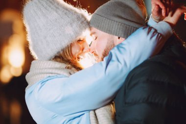 Kış tatili gebeliği. Genç bir çiftin açık hava gece portresi. Avrupa sokaklarında poz vermek.