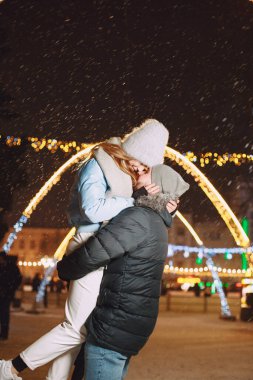 Kış tatili gebeliği. Genç bir çiftin açık hava gece portresi. Avrupa sokaklarında poz vermek.