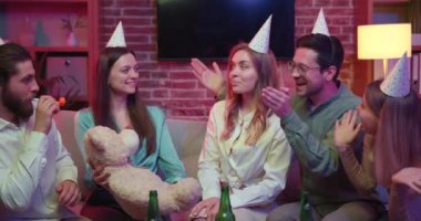 Gençler evde toplandı. Parti şapkaları takıyorlar, abur cubur yiyorlar, kağıt bardaklardan içiyorlar. Doğum günü partisinde eğleniyorum.,