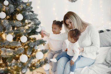 İnsanlar Noel için hazırlanıyor. Anne kızlarıyla oynuyor. Aile şenlik odasında dinleniyor. Kazaklı bir çocuk..