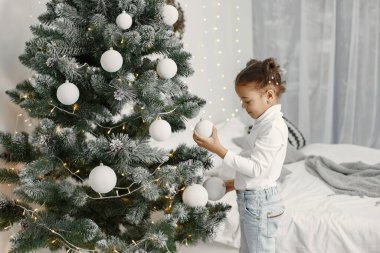 Beyaz kazaklı bir çocuk. Kızım Noel ağacının yanında duruyor..