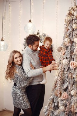 İnsanlar Noel için hazırlanıyor. İnsanlar kızlarıyla oynuyorlar. Aile şenlik odasında dinleniyor. Kırmızı elbiseli çocuk..