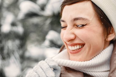 Kahverengi kacketli bir kadının yakın plan portresi. Karlı bir günde ayakta duran kadın.