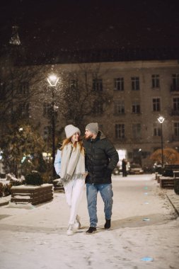 Kış tatili gebeliği. Genç bir çiftin açık hava gece portresi. Avrupa sokaklarında poz vermek.