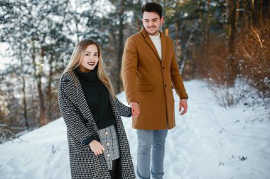 karlı bir günde parkta yürüyen mutlu genç çift