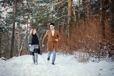 karlı bir günde parkta yürüyen mutlu genç çift