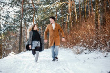 karlı bir günde parkta yürüyen mutlu genç çift