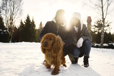 İnsanlar dışarıda yürüyor. Kış günü. Köpekli Afrikalı çift.