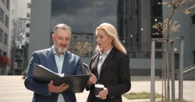 Resmi olarak çalışan beyaz yakalı işçiler şehir merkezindeki şehir merkezindeki sokakta dikiliyorlar. Belgeleri inceleyen iş arkadaşları.