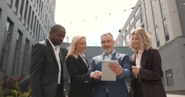 Grup başarılı iş adamları dijital tablet kullanarak takım elbiseli. Office arka plan.