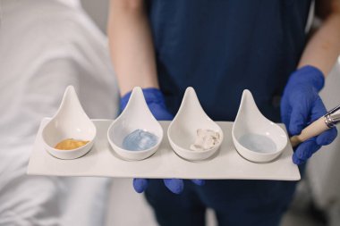 Dört farklı kozmetik krem kavanozunu kapat. Kozmetik uzmanı cilde sürmeden önce nemlendirici krem losyonları ve diğer maskeleri tutuyor. Kendini tedavi etme kavramı.