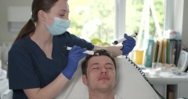 Profesyonel dermatolog tarafından cilt bakımı gören genç bir adam. Kozmetik Merkezi 'nde cihaz terapisi..