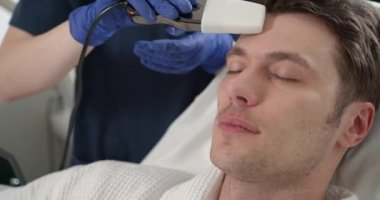 Kozmetik uzmanı insanı bir yüz üzerinde tedavi edici bir prosedür haline getiriyor. Güzellik uzmanı yüz işlemleri için elektriksel impulslar kullanıyor..