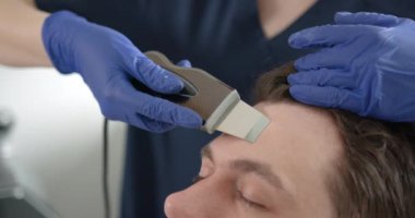 Kozmetik uzmanı insanı bir yüz üzerinde tedavi edici bir prosedür haline getiriyor. Güzellik uzmanı yüz işlemleri için elektriksel impulslar kullanıyor..