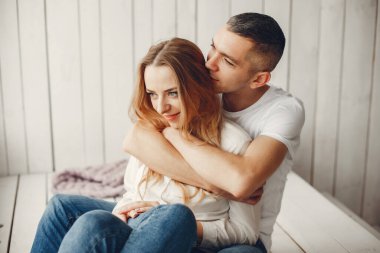 Evde oturan bir çift. Güzel sarışın kocası ile. Beyaz tişörtlü adam