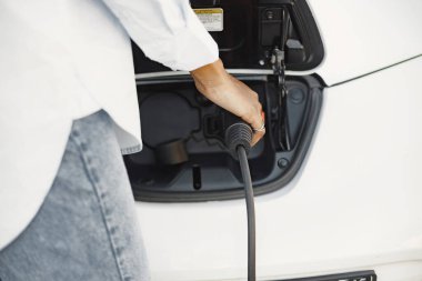 Islam black girl charging electro car. Eco car.