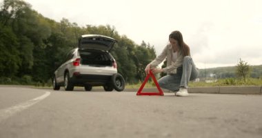 Broken down car on a road with red warning triangle. Flat tire problem.