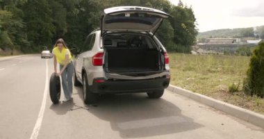 Girl changing a punctured tire at the car. Repair of cars on the road. Accident concept.